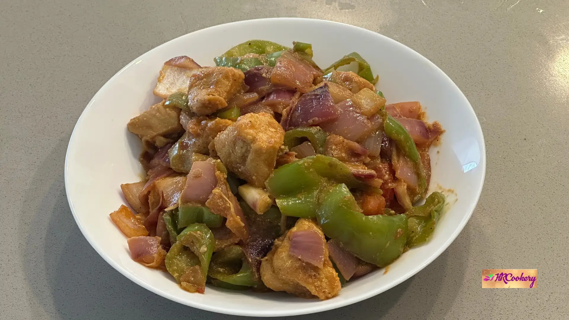 Sri Lankan deviled chili chicken stir-fry with chicken breast, green bell peppers, and red onions in a spicy glossy sauce.
