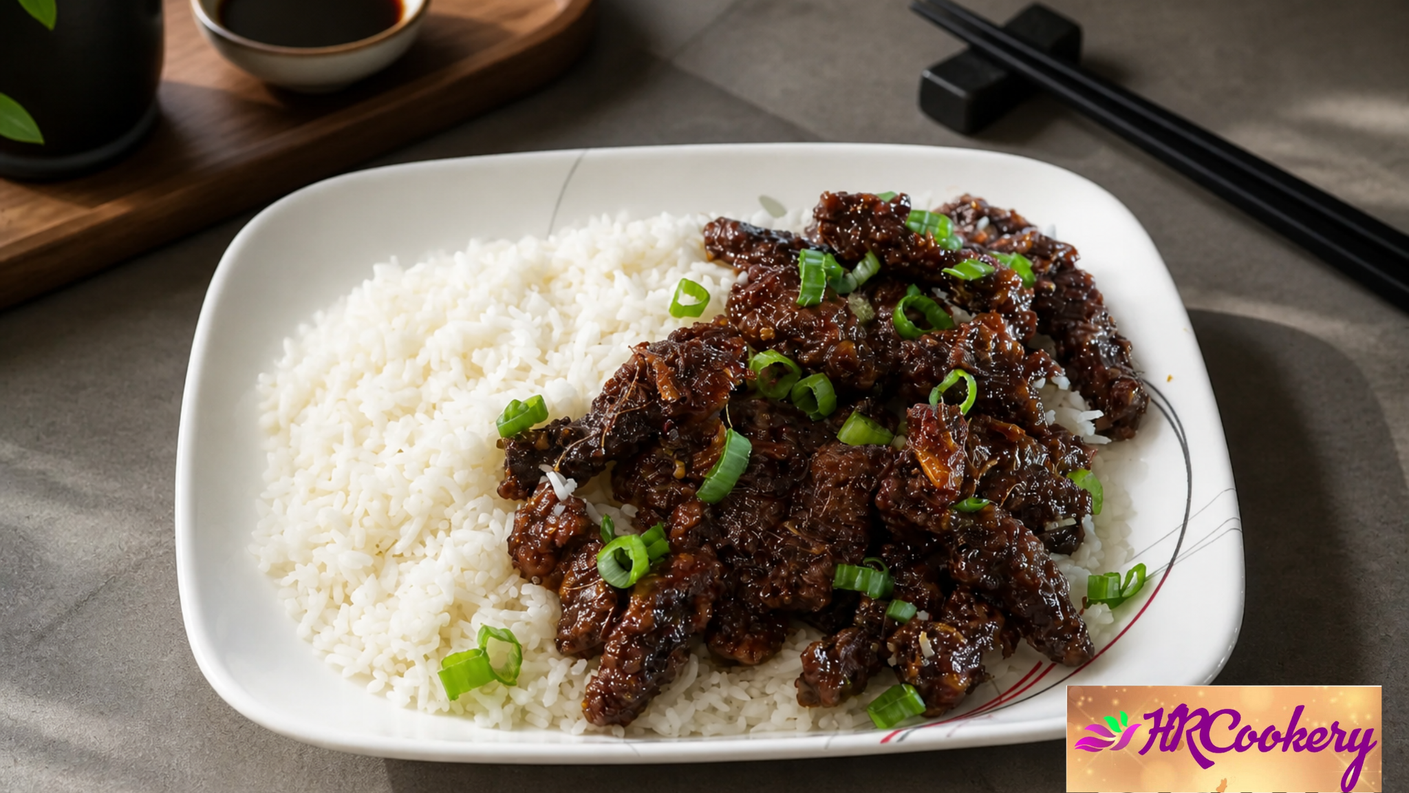 Crispy ginger beef served over steamed white rice and garnished with sliced green onions on a white plate.