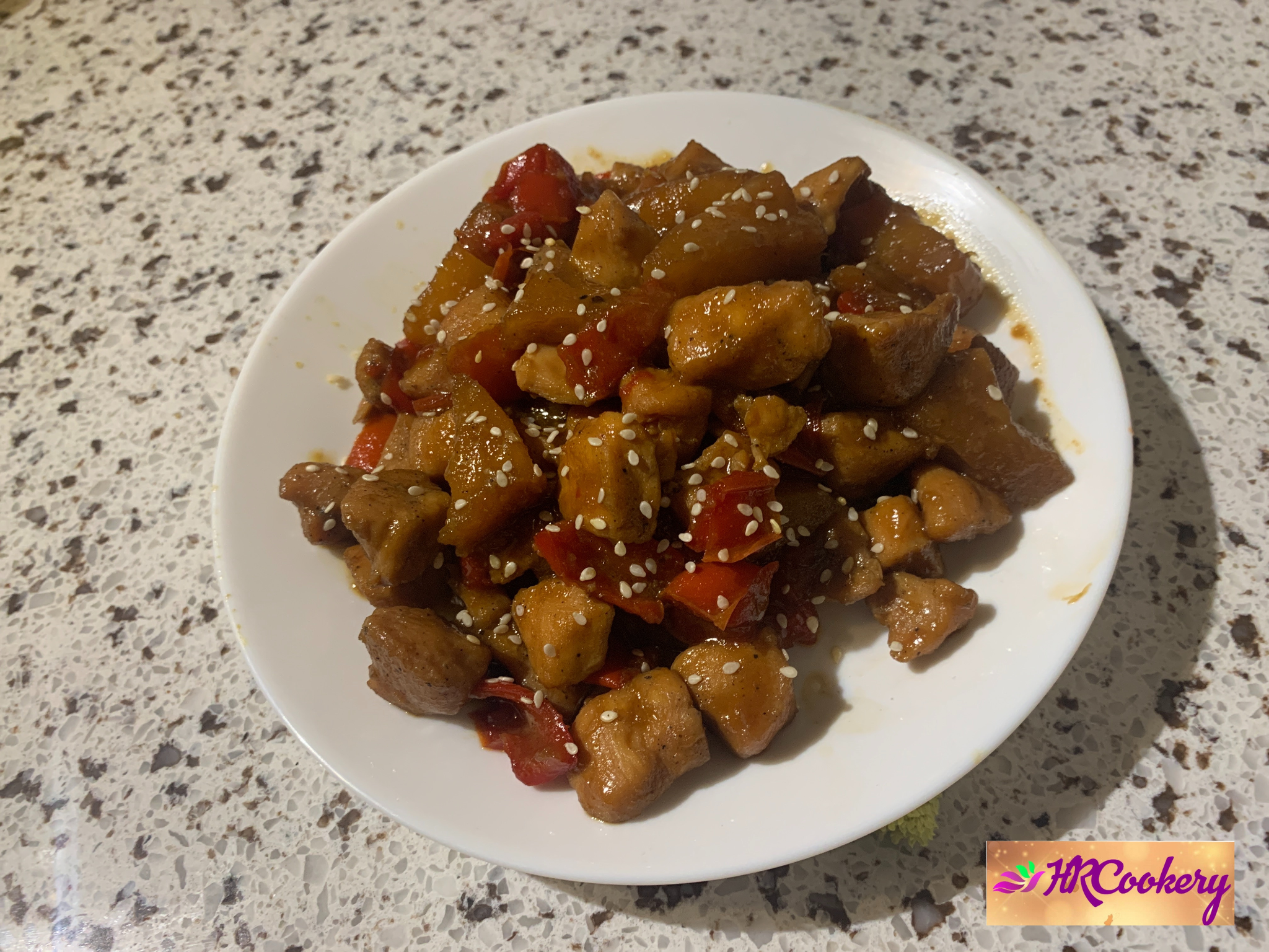 Juicy pineapple chicken pieces garnished with fresh green onions and served in a vibrant bowl, with pineapple chunks scattered around.