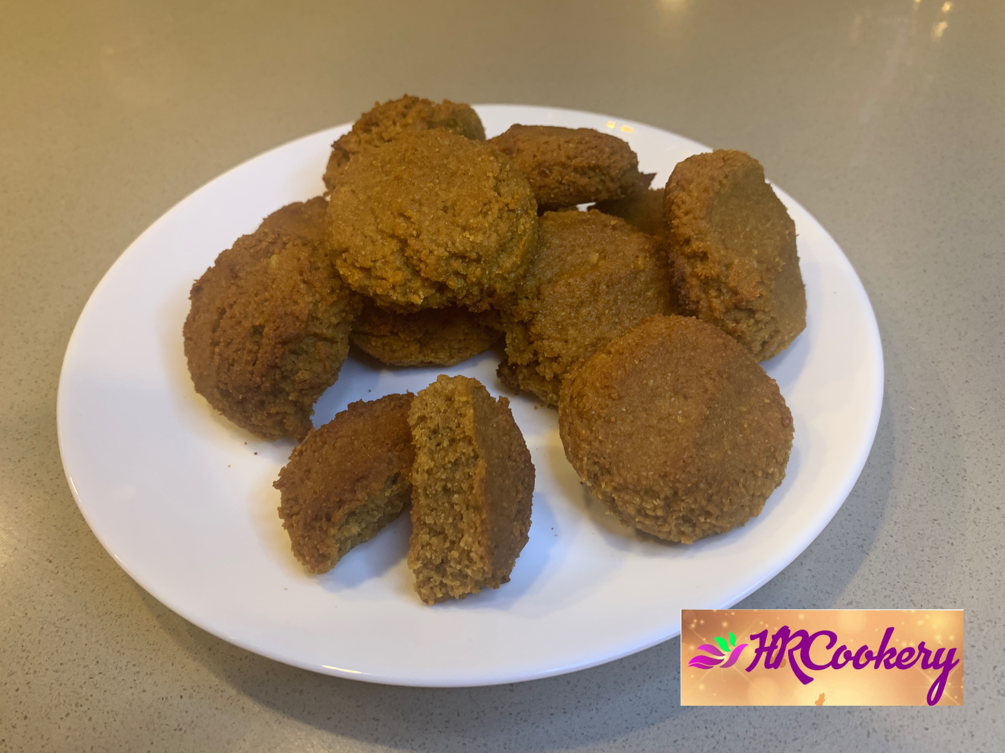 A plate of freshly baked cottage cheese cookies, golden brown and sprinkled with powdered sugar, displayed on a rustic wooden table.