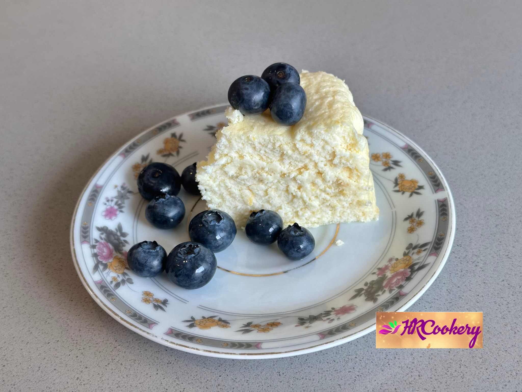 Yogurt cake on a white plate, beautifully decorated with fresh blueberries and a dusting of powdered sugar.