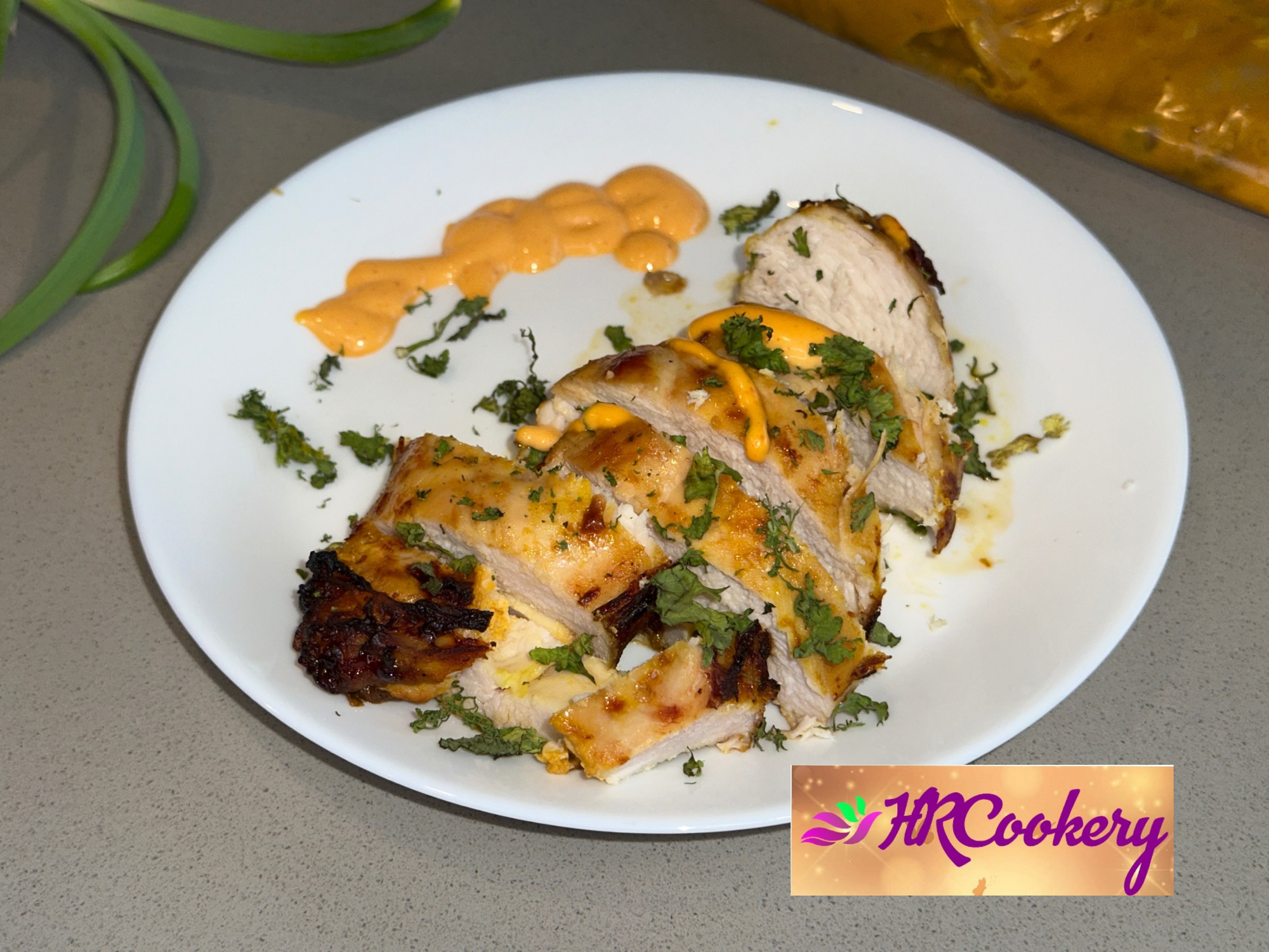 Grilled mango chicken on a white plate, drizzled with a tangy mango sauce and garnished with fresh herbs.