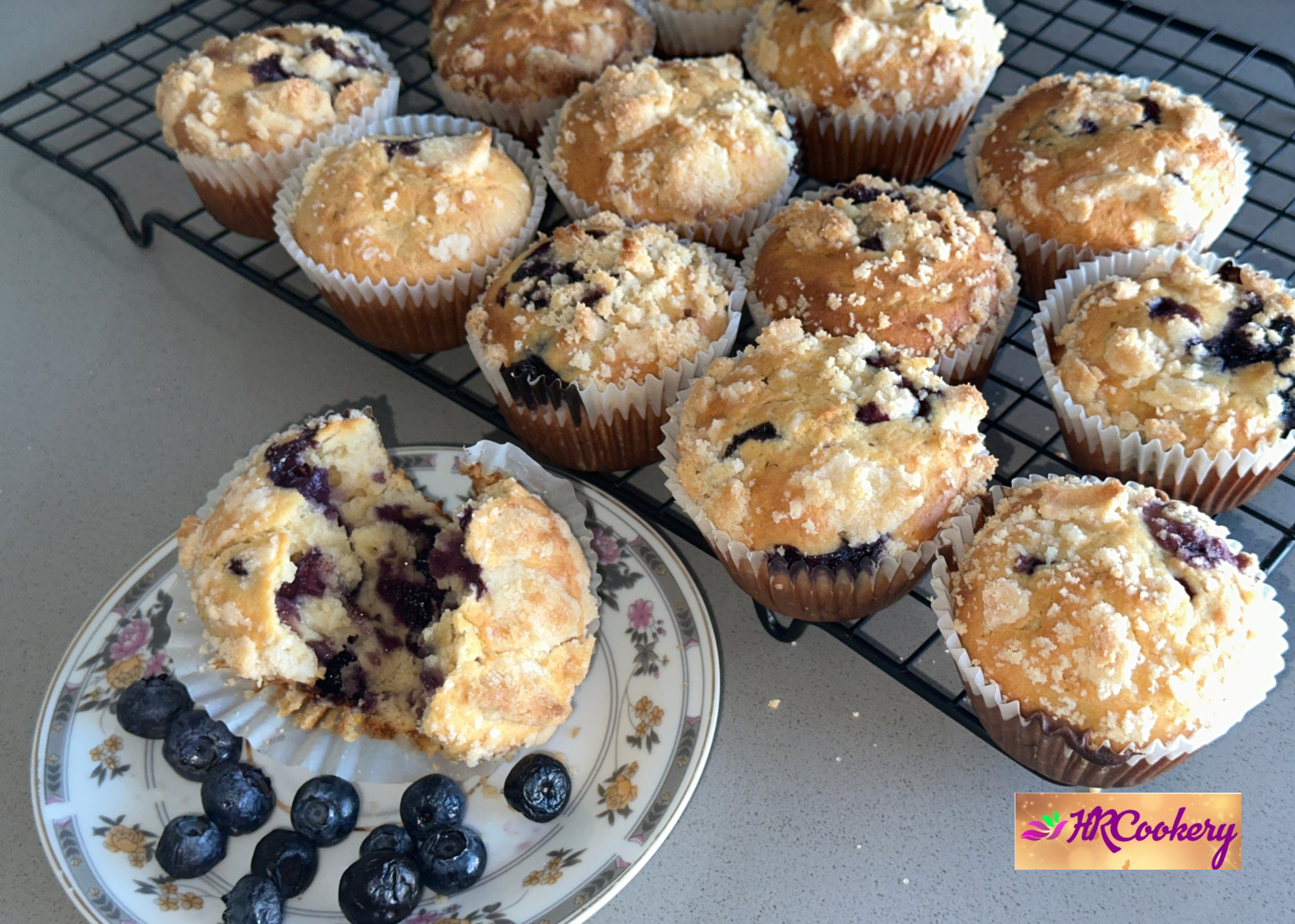 Freshly baked blueberry muffins with golden tops and visible blueberries, arranged on a cooling rack.