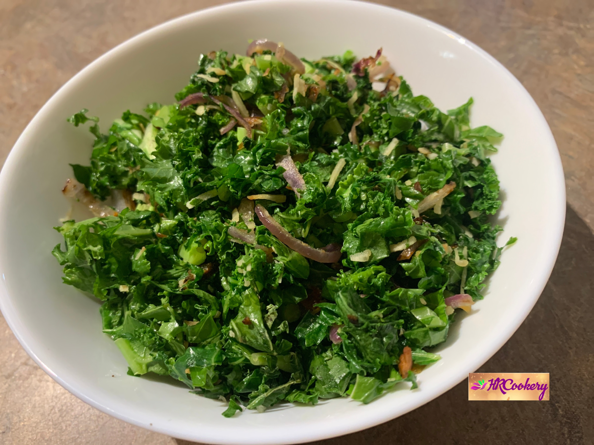 Sri Lankan kale stir-fry with onion and garlic in a white bowl.