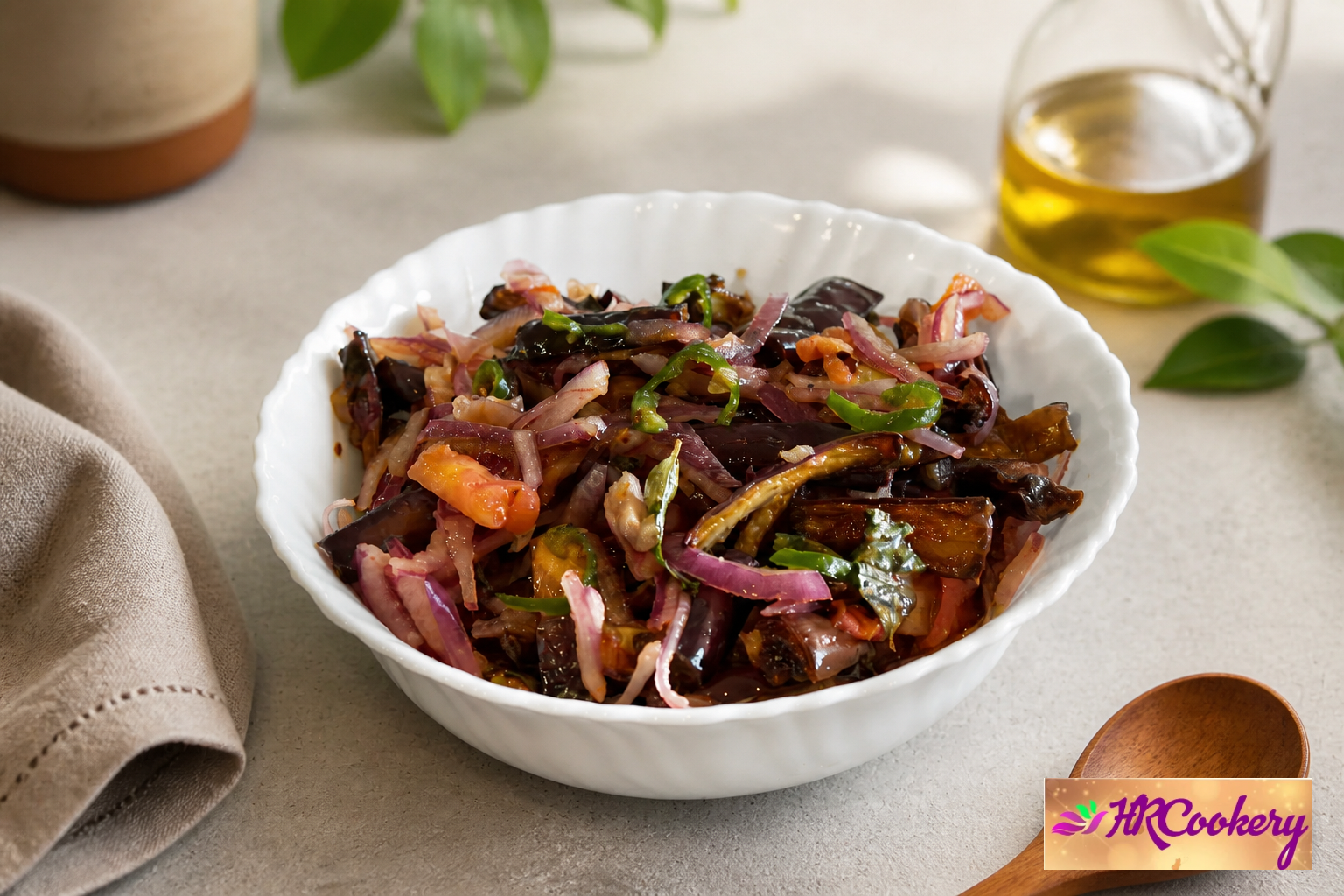 Sri Lankan fried eggplant (brinjal) salad with red onions, green chilies, tomatoes, and curry leaves in a white serving bowl.